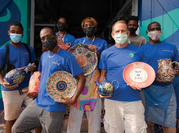 Earthworks Pottery team holding ceramics at the studio in Barbados